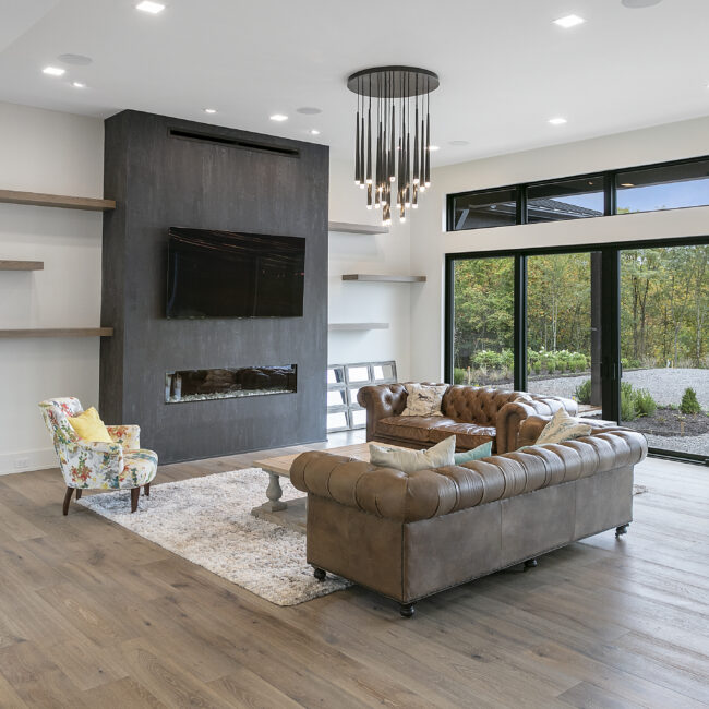 Living room with linear fireplace and tufted leather sofas in Rocky Top Hideaway, a custom home by Mike Stevens Homes