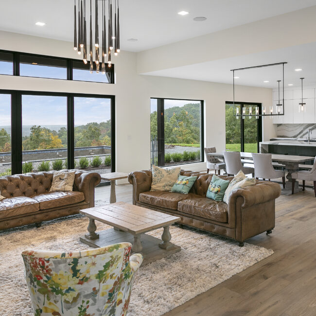 Living room with brown leather sofas and floral accent chair in Rocky Top Hideaway, a custom home by Mike Stevens Homes
