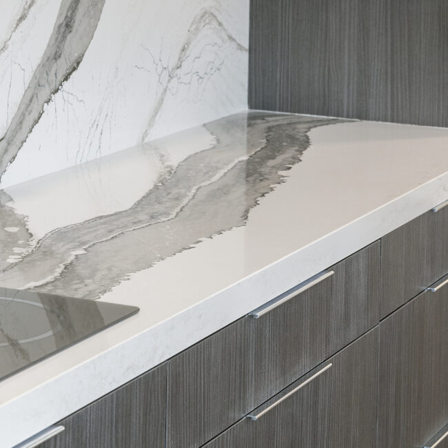 Veined quartz counter beside induction cooktop in Rocky Top Hideaway, a custom home by Mike Stevens Homes