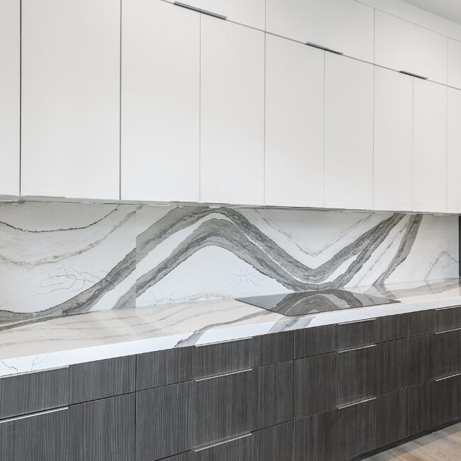 Gray-veined quartz backsplash below white upper cabinets in Rocky Top Hideaway, a custom home by Mike Stevens Homes