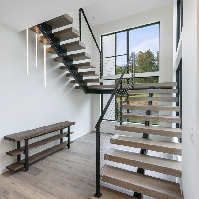 Open-tread steel staircase with wood steps and bench in Rocky Top Hideaway, a custom home by Mike Stevens Homes
