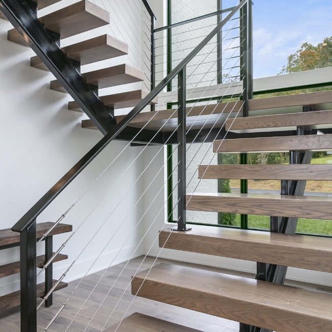 Open wood-tread staircase with black steel railing in Rocky Top Hideaway, a custom home by Mike Stevens Homes