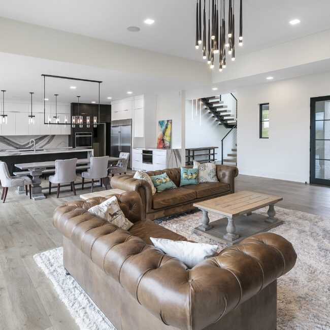 Living room with leather sofa and floating staircase in Rocky Top Hideaway, a custom home by Mike Stevens Homes