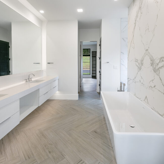 Primary bath with soaking tub beside white double vanity in Rocky Top Hideaway, a custom home by Mike Stevens Homes