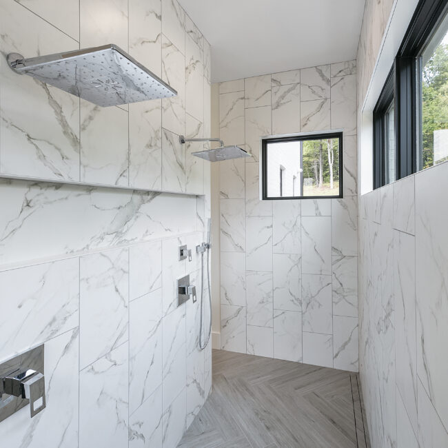 Walk-in shower with marble-look tile and rain head in Rocky Top Hideaway, a custom home by Mike Stevens Homes