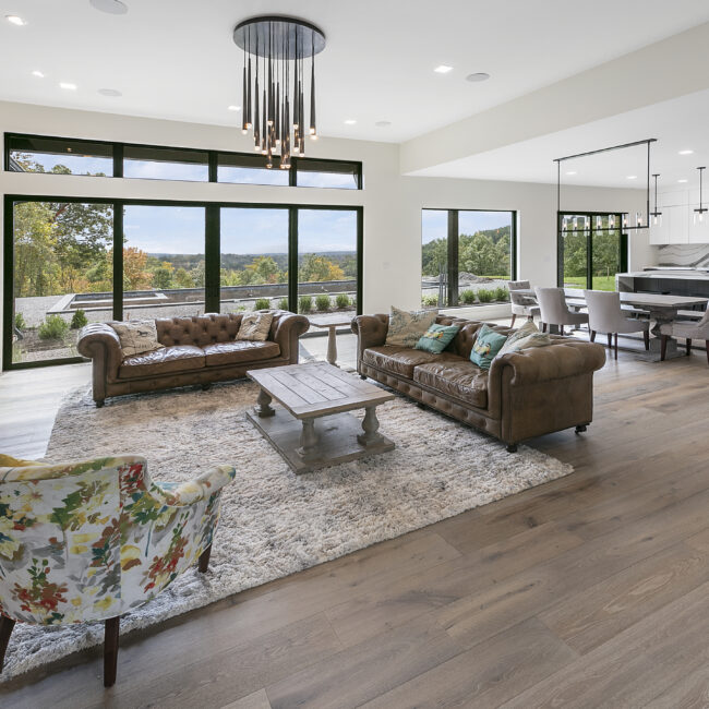 Great room with leather sofas and rug beneath wall of windows in Rocky Top Hideaway, a custom home by Mike Stevens Homes