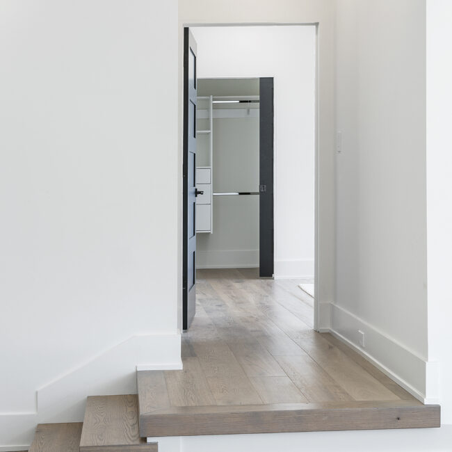 Step-down entry with wood treads and hallway to closet in Rocky Top Hideaway, a custom home by Mike Stevens Homes