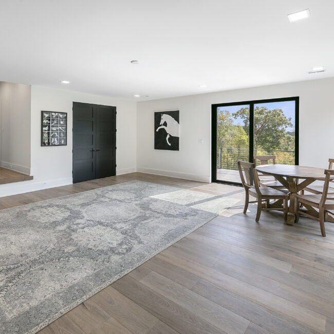 Living room with gray rug and dining table by glass doors in Rocky Top Hideaway, a custom home by Mike Stevens Homes