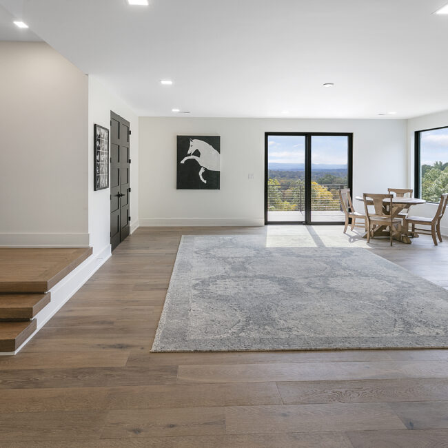 Open room with gray area rug and wood floors in Rocky Top Hideaway, a custom home by Mike Stevens Homes