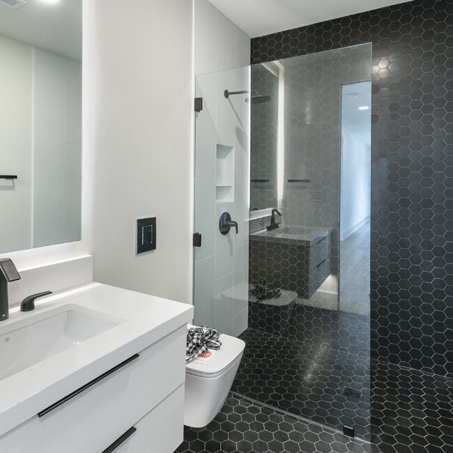 Bathroom with black hexagon tile shower and white vanity in Rocky Top Hideaway, a custom home by Mike Stevens Homes