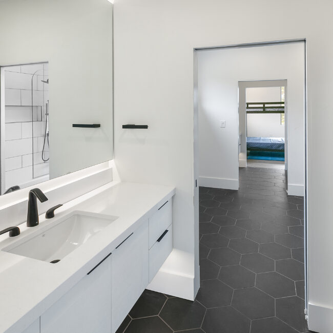 Double vanity beside black hexagon tile floor in Rocky Top Hideaway, a custom home by Mike Stevens Homes