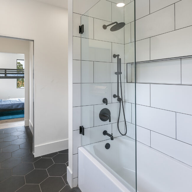 Tub with white subway-tile surround and black fixtures in Rocky Top Hideaway, a custom home by Mike Stevens Homes