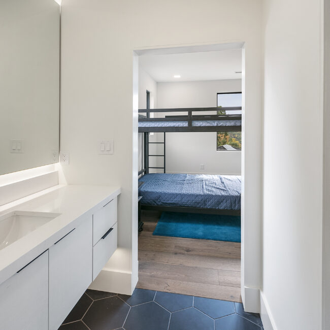 Bedroom with bunk beds and blue area rug in Rocky Top Hideaway, a custom home by Mike Stevens Homes