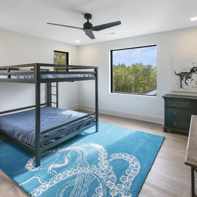 Bunk bed room with teal octopus-motif rug in Rocky Top Hideaway, a custom home by Mike Stevens Homes