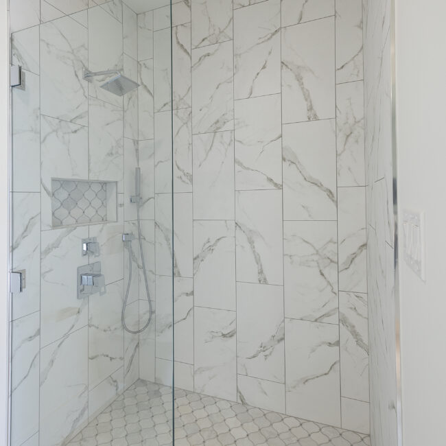 Shower with marble-look tile and recessed niche in Rocky Top Hideaway, a custom home by Mike Stevens Homes