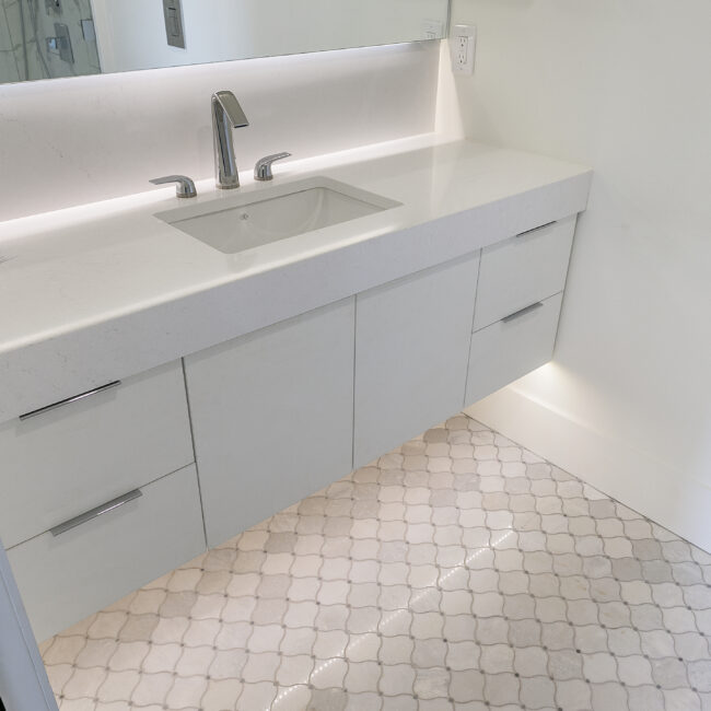 Vanity with undermount sink and glossy white cabinets in Rocky Top Hideaway, a custom home by Mike Stevens Homes