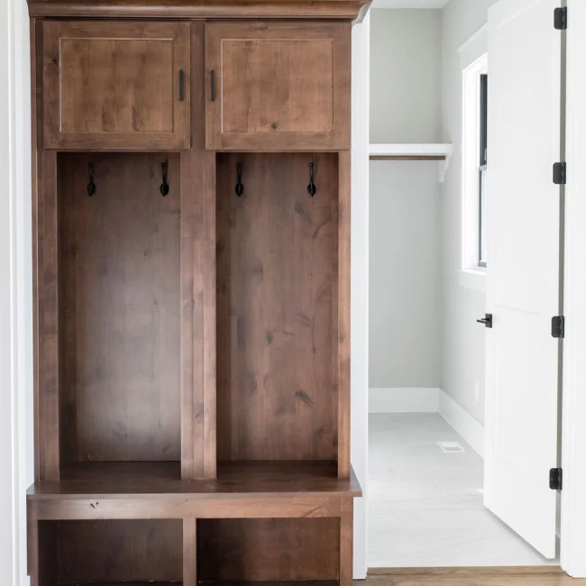 Mudroom with wood lockers and black-framed door in Rural Farmhouse, a custom home by Mike Stevens Homes