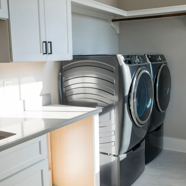 Laundry room with front-loading washer and dryer in Rural Farmhouse, a custom home by Mike Stevens Homes