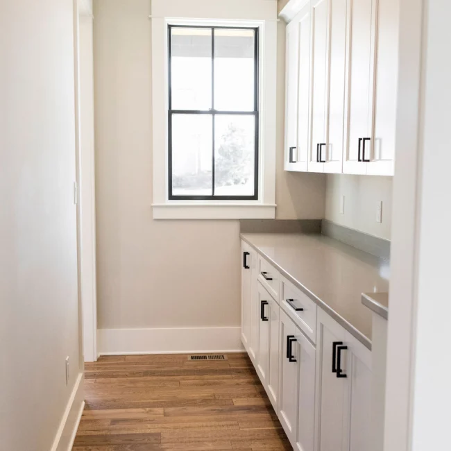 Butler pantry with white cabinetry beside a window in Rural Farmhouse, a custom home by Mike Stevens Homes