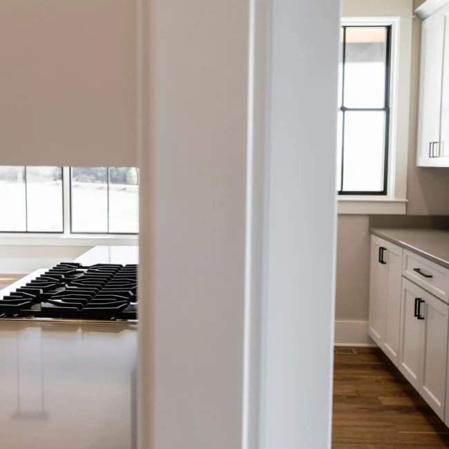Kitchen with gas range and white cabinetry by window in Rural Farmhouse, a custom home by Mike Stevens Homes