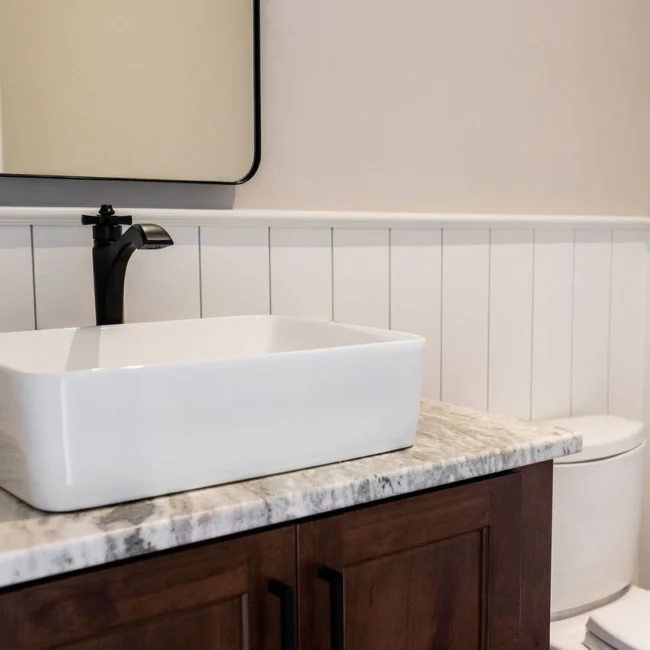 Black faucet and white vessel sink above wood vanity in Rural Farmhouse, a custom home by Mike Stevens Homes