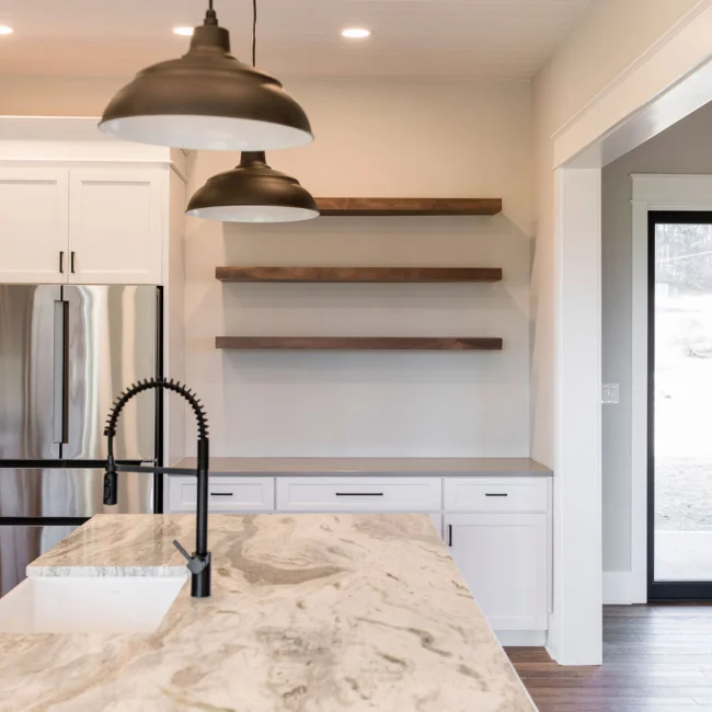 Kitchen with floating wood shelves and black pendants in Rural Farmhouse, a custom home by Mike Stevens Homes