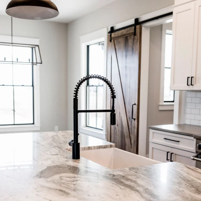 Kitchen island with farmhouse sink and barn door in Rural Farmhouse, a custom home by Mike Stevens Homes