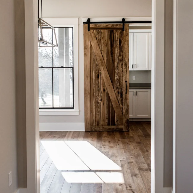 Barn door to white pantry with bright window light in Rural Farmhouse, a custom home by Mike Stevens Homes