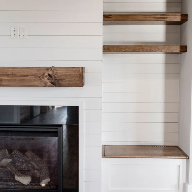 Shiplap fireplace wall with rustic wood mantel in Rural Farmhouse, a custom home by Mike Stevens Homes
