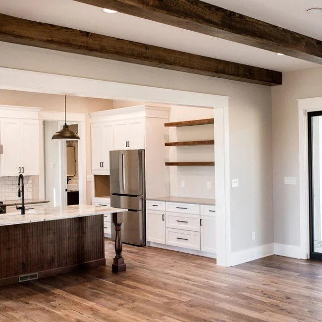 Open kitchen with exposed wood beams and island in Rural Farmhouse, a custom home by Mike Stevens Homes