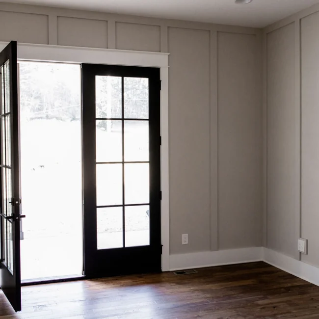 Board-and-batten wall beside black French door in Rural Farmhouse, a custom home by Mike Stevens Homes