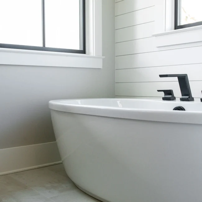 Close-up of freestanding white tub and matte black faucet in Rural Farmhouse, a custom home by Mike Stevens Homes