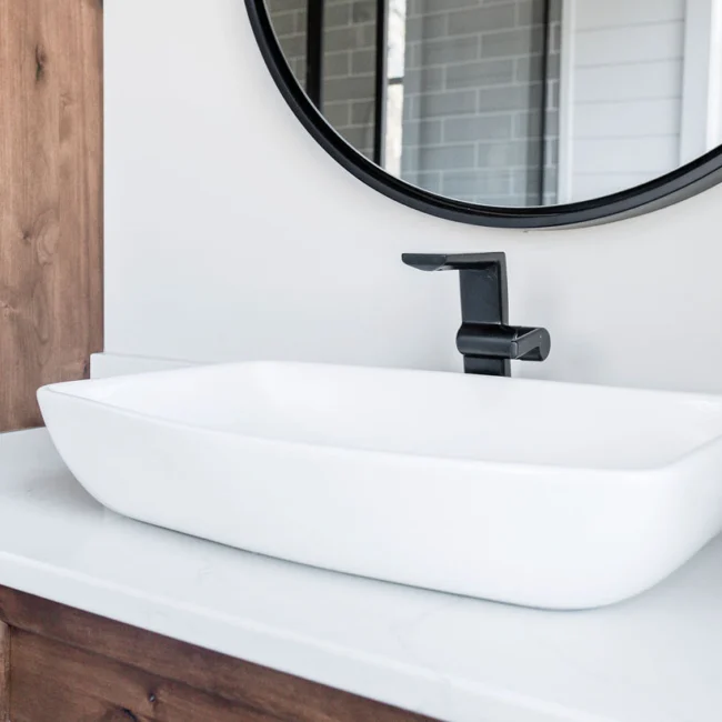 Vessel sink with black faucet on wood cabinet in Rural Farmhouse, a custom home by Mike Stevens Homes