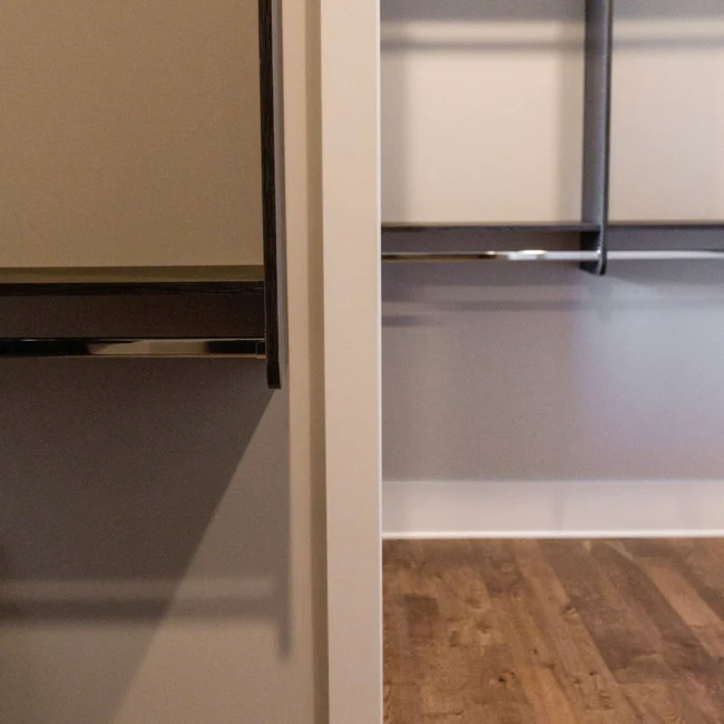 Walk-in closet with metal rod and wood flooring in Rural Farmhouse, a custom home by Mike Stevens Homes