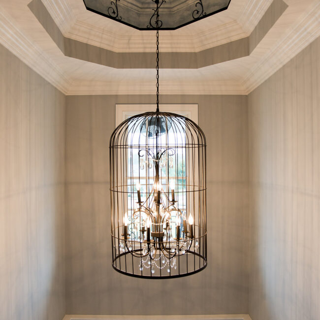 Two-story foyer with birdcage chandelier under tray ceiling in Haunted Mansion Homage, a custom home by Mike Stevens Homes