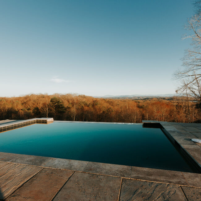 Infinity-edge pool overlooking autumn woods in Mountain Vista by Mike Stevens Homes