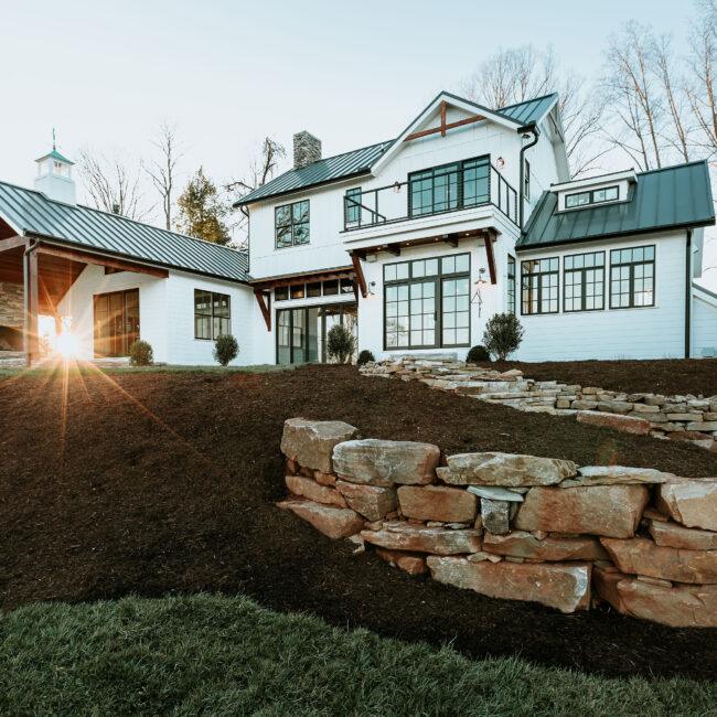 White farmhouse exterior with stacked stone retaining wall in Mountain Vista by Mike Stevens Homes