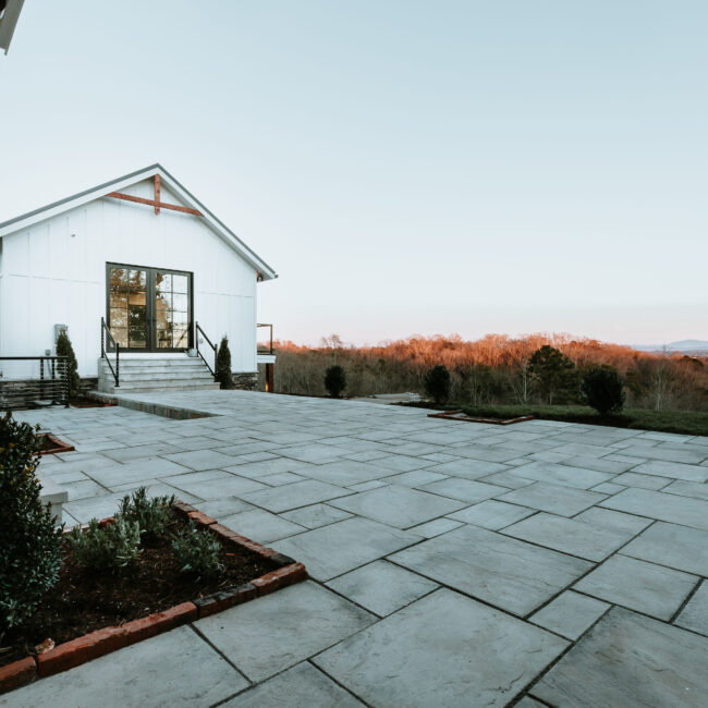 Flagstone patio with garden bed and white home with gabled entry in Mountain Vista by Mike Stevens Homes