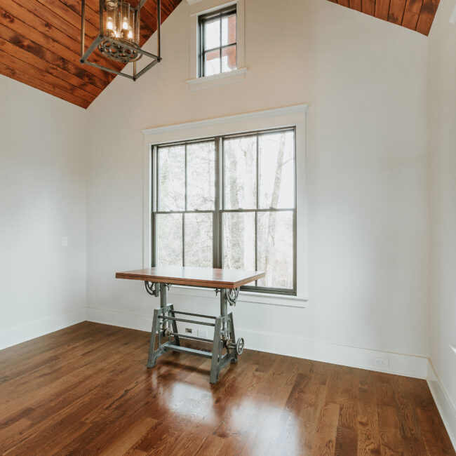 Bright office with wood-top drafting table and large paned window in Mountain Vista by Mike Stevens Homes
