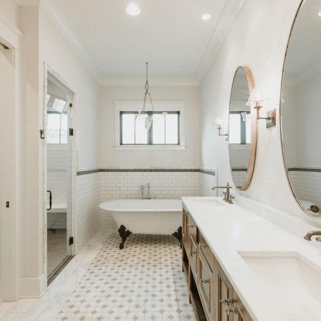 Bathroom with clawfoot tub, round mirror and wood vanity in Mountain Vista by Mike Stevens Homes
