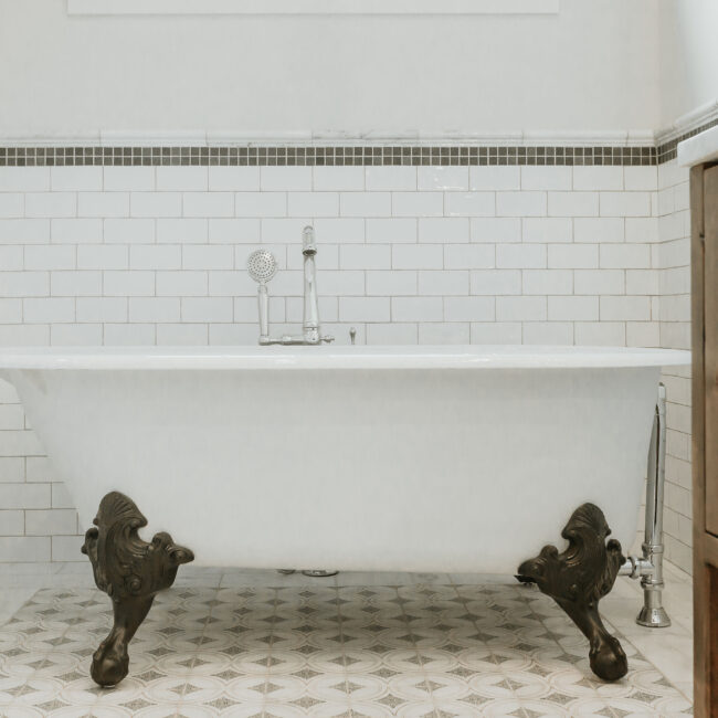 Clawfoot tub with cast iron feet against subway tile and dark tile trim in Mountain Vista by Mike Stevens Homes