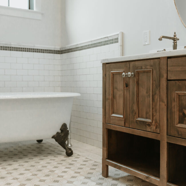 Clawfoot tub beside wood vanity with white sink in Mountain Vista by Mike Stevens Homes
