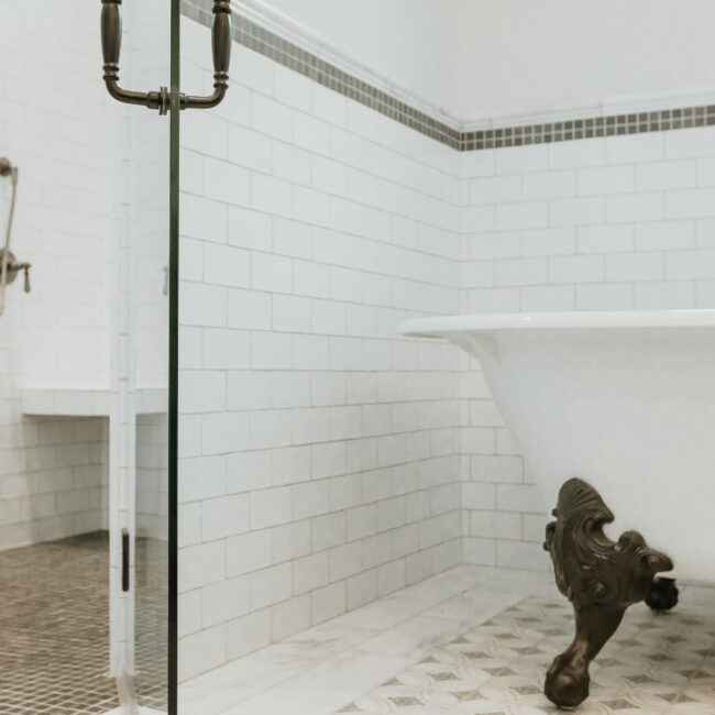 Clawfoot tub beyond frameless glass shower in subway-tiled bathroom in Mountain Vista by Mike Stevens Homes