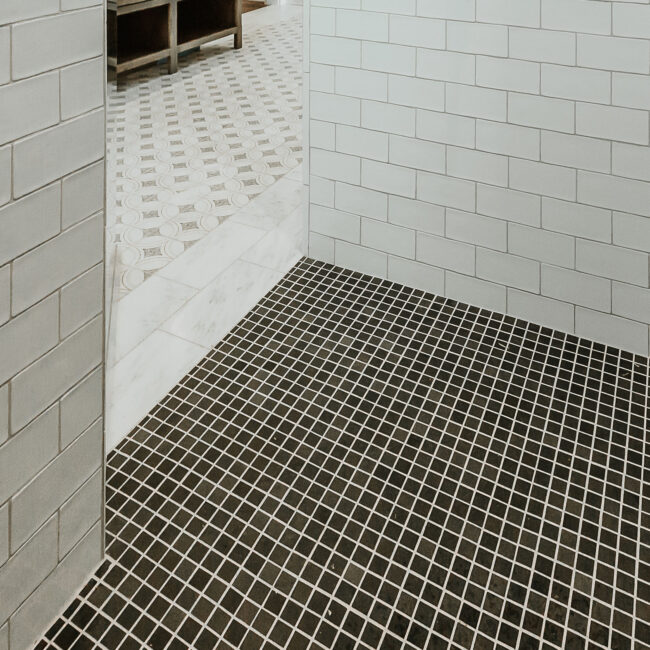 Shower entry with black hex tile floor and gray subway tile walls in Mountain Vista by Mike Stevens Homes