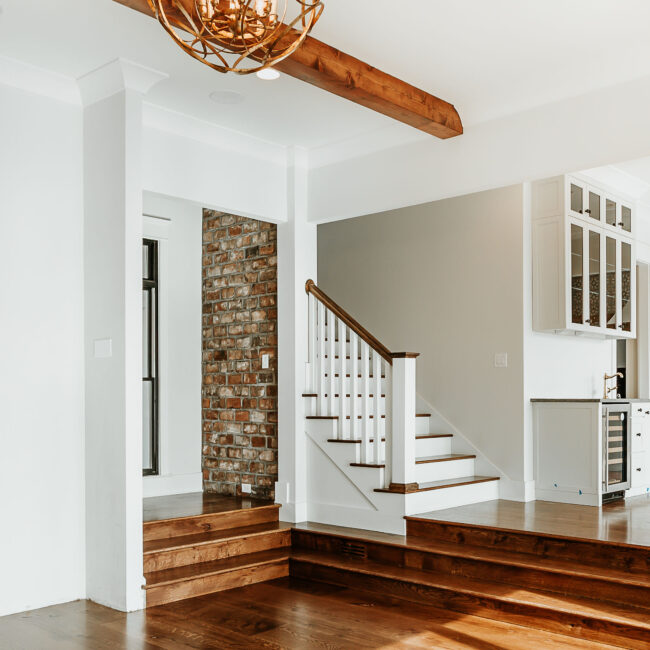 Foyer with wood-tread staircase, brick accent wall and built-in cabinetry in Mountain Vista by Mike Stevens Homes