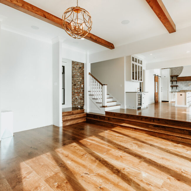 Open main level with wood floors, stair and exposed wood beams in Mountain Vista by Mike Stevens Homes