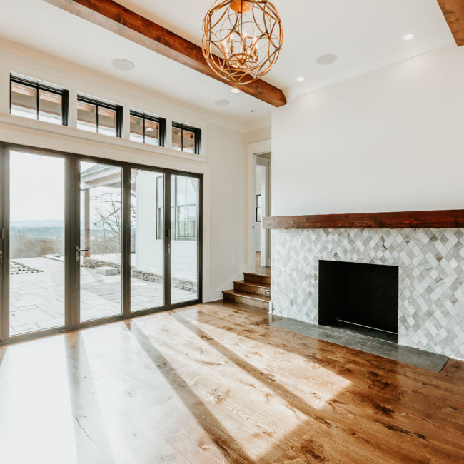 Great room with stone fireplace, sliding glass doors and wood beams in Mountain Vista by Mike Stevens Homes