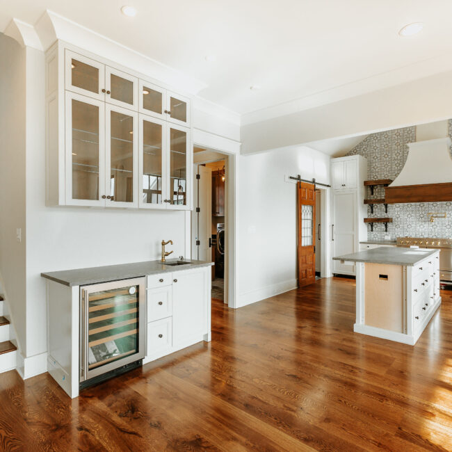 Kitchen with beverage fridge, glass cabinets and island in Mountain Vista by Mike Stevens Homes