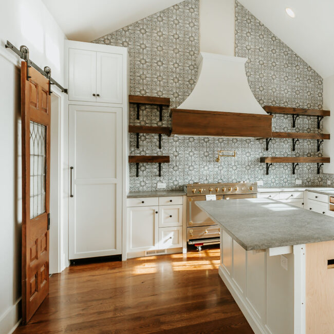 Kitchen with white hood, tiled backsplash and tall pantry in Mountain Vista by Mike Stevens Homes