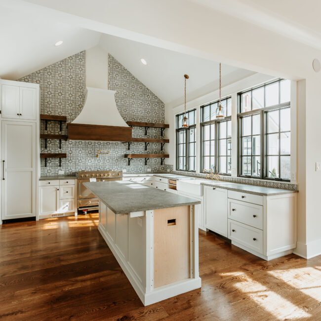 Kitchen island with gray countertop and window wall in Mountain Vista by Mike Stevens Homes